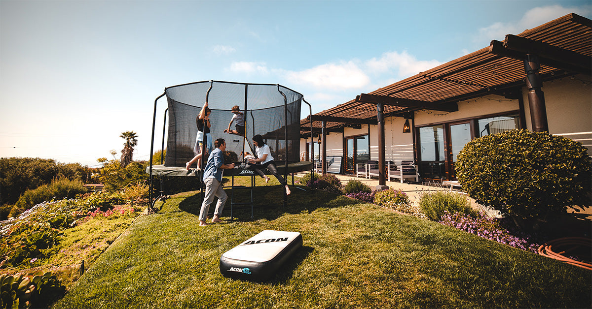 A family spending time together on a round trampoline with enclosure