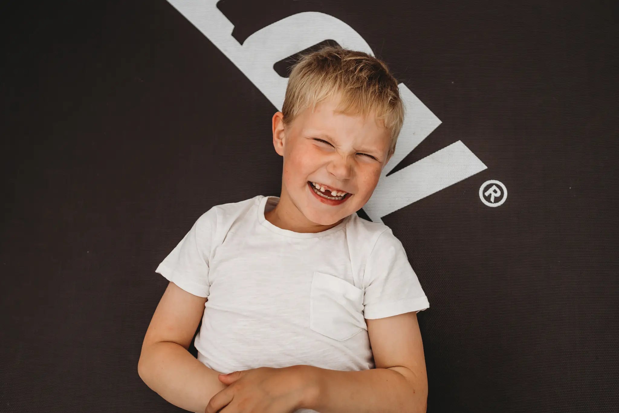 Smiling young boy laying on a Acon trampoline mat.
