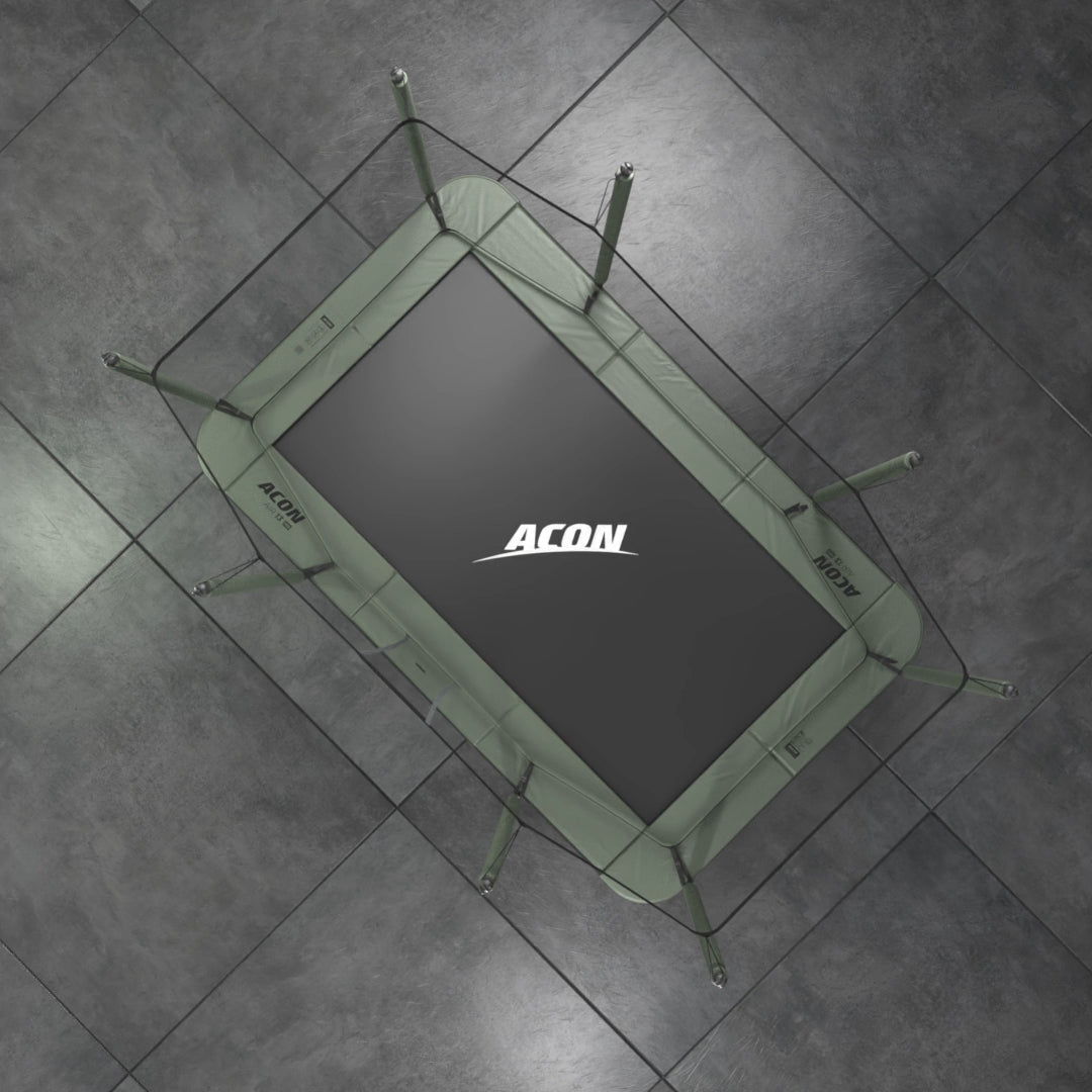 Acon HD rectangular trampoline from bird’s eye view on a grey background. The black trampoline mat has ACON logo on it in white and the paddings are green