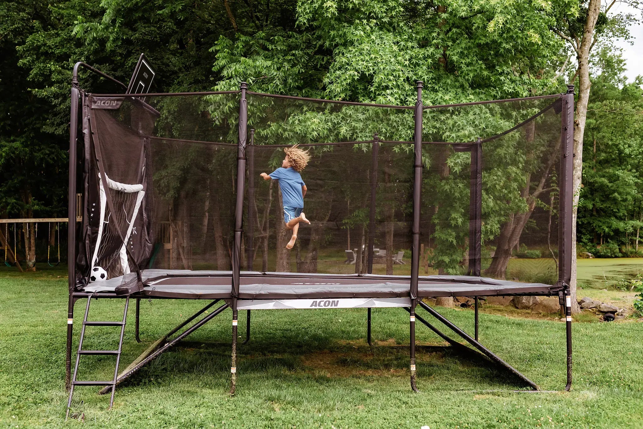 Child jumping on an Acon trampoline with a soccer goal attachment.