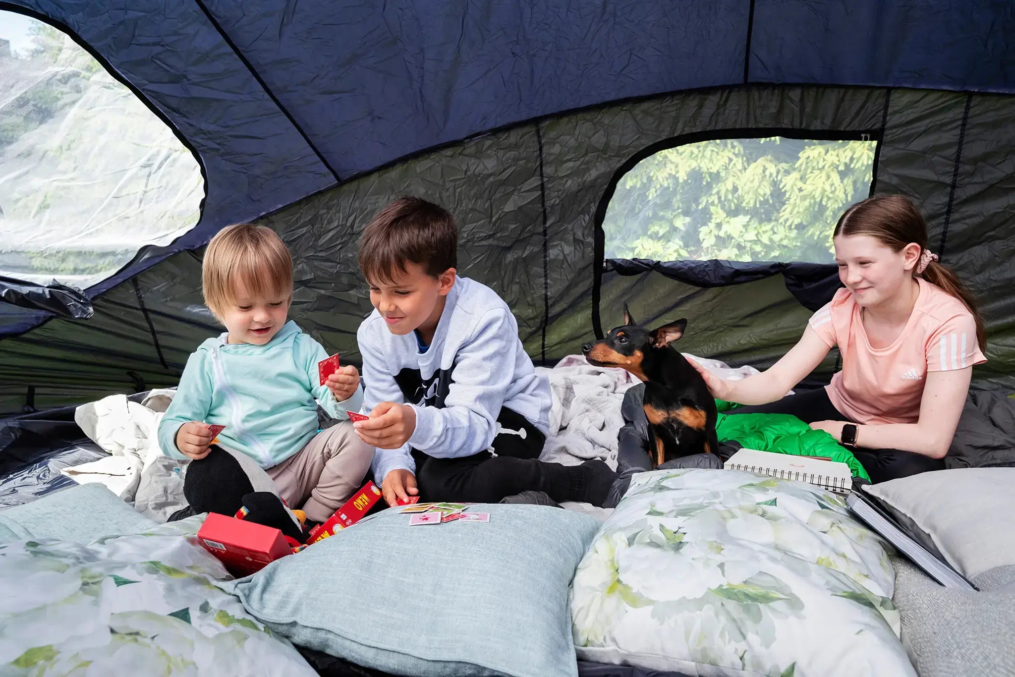 Group of three kids hanging inside of an Acon trampoline tent with a dog.