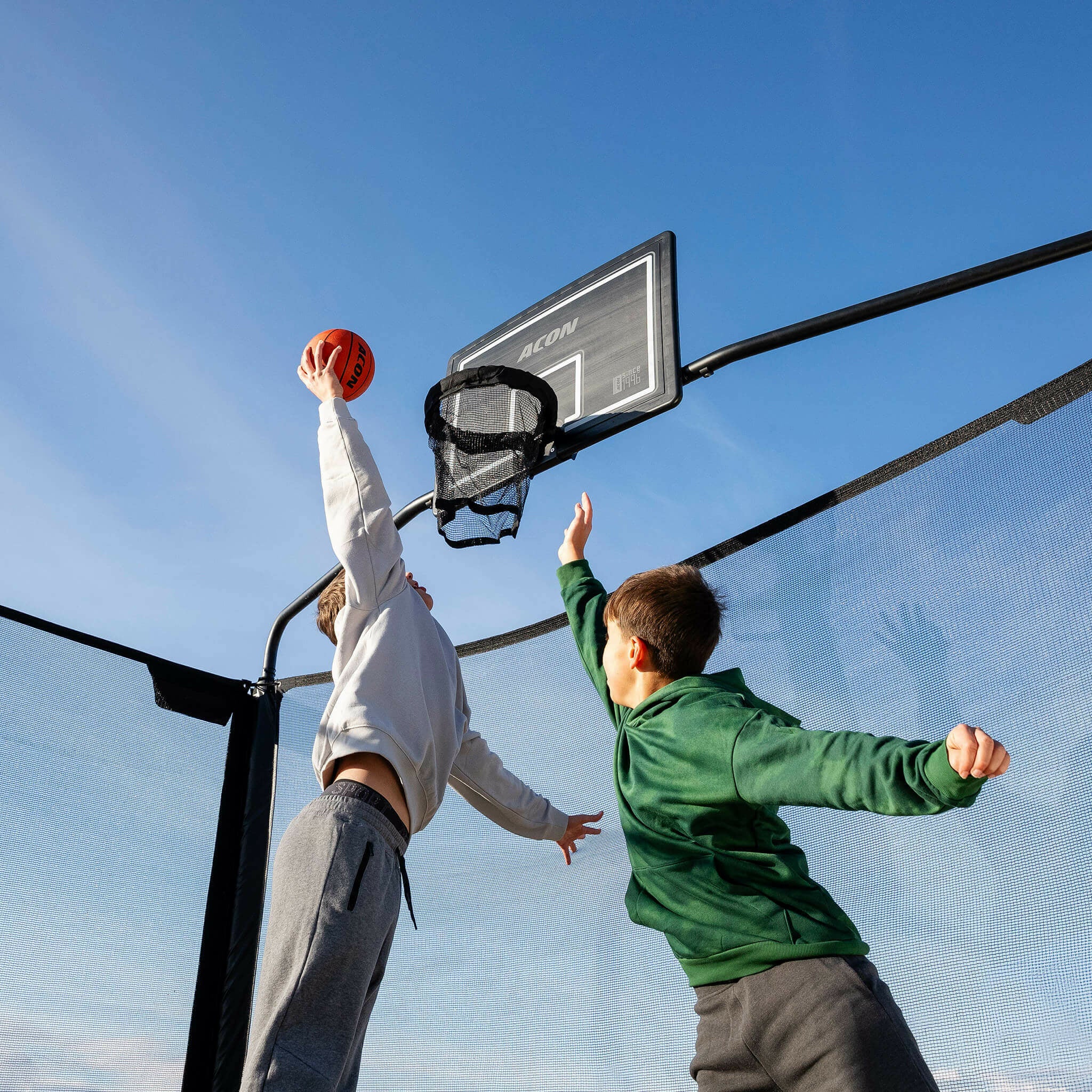 Two boys playing basketball on the Acon X Trampoline.