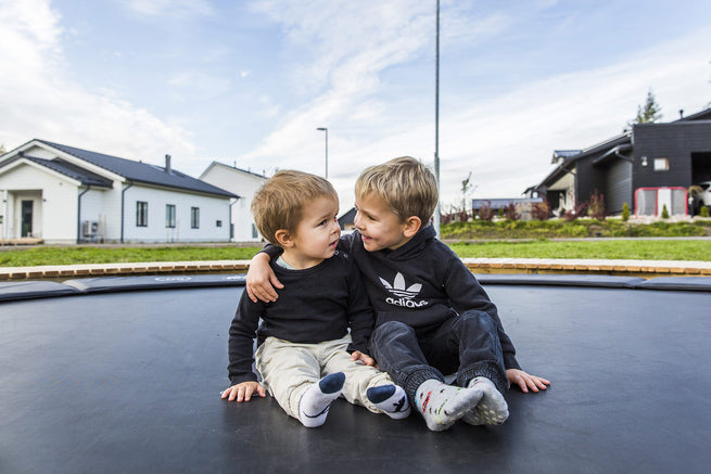 Two kids sitting and hugging on a round trampoline