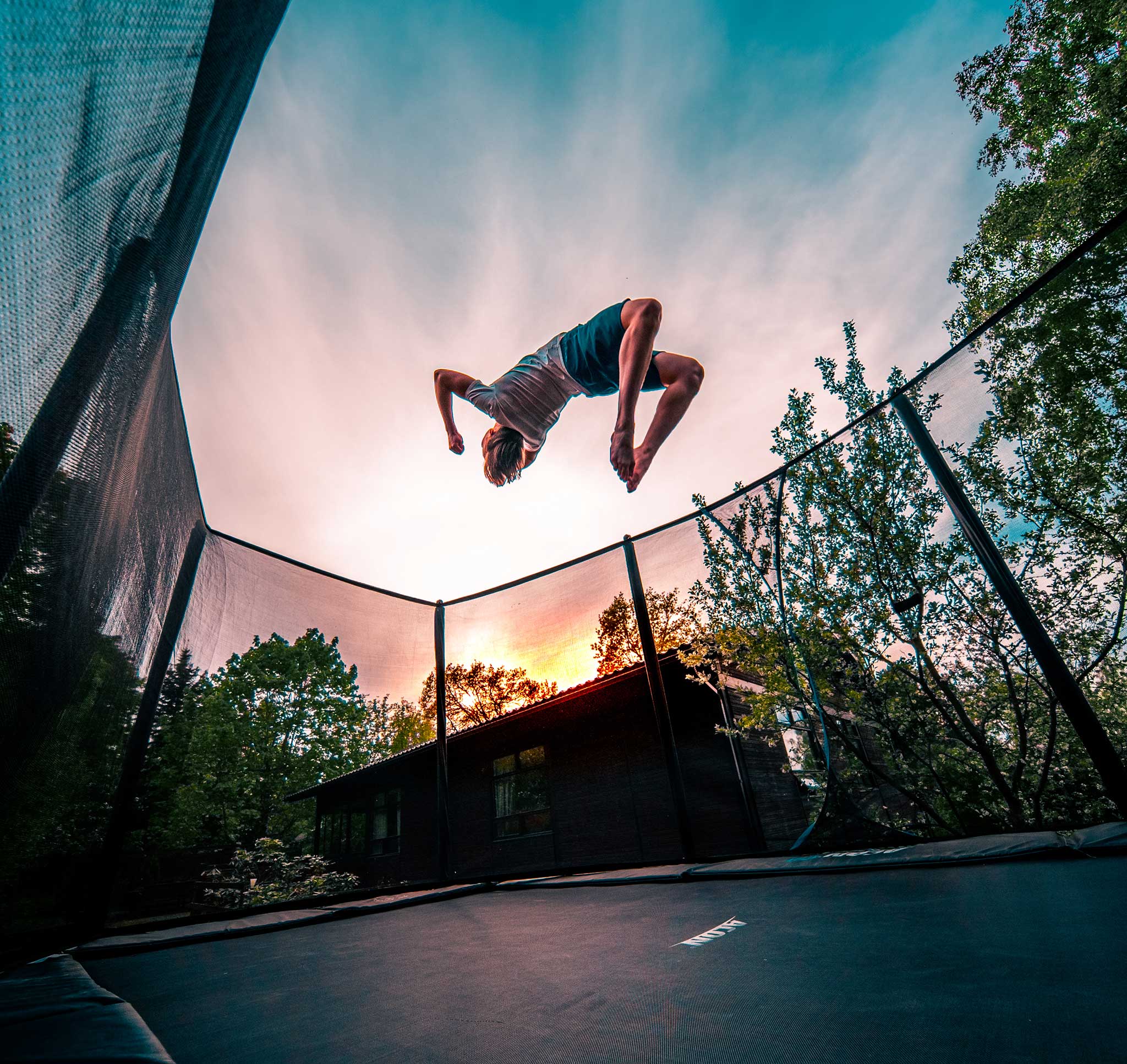 A boy doing a backflip on an Acon 16 HD trampoline.