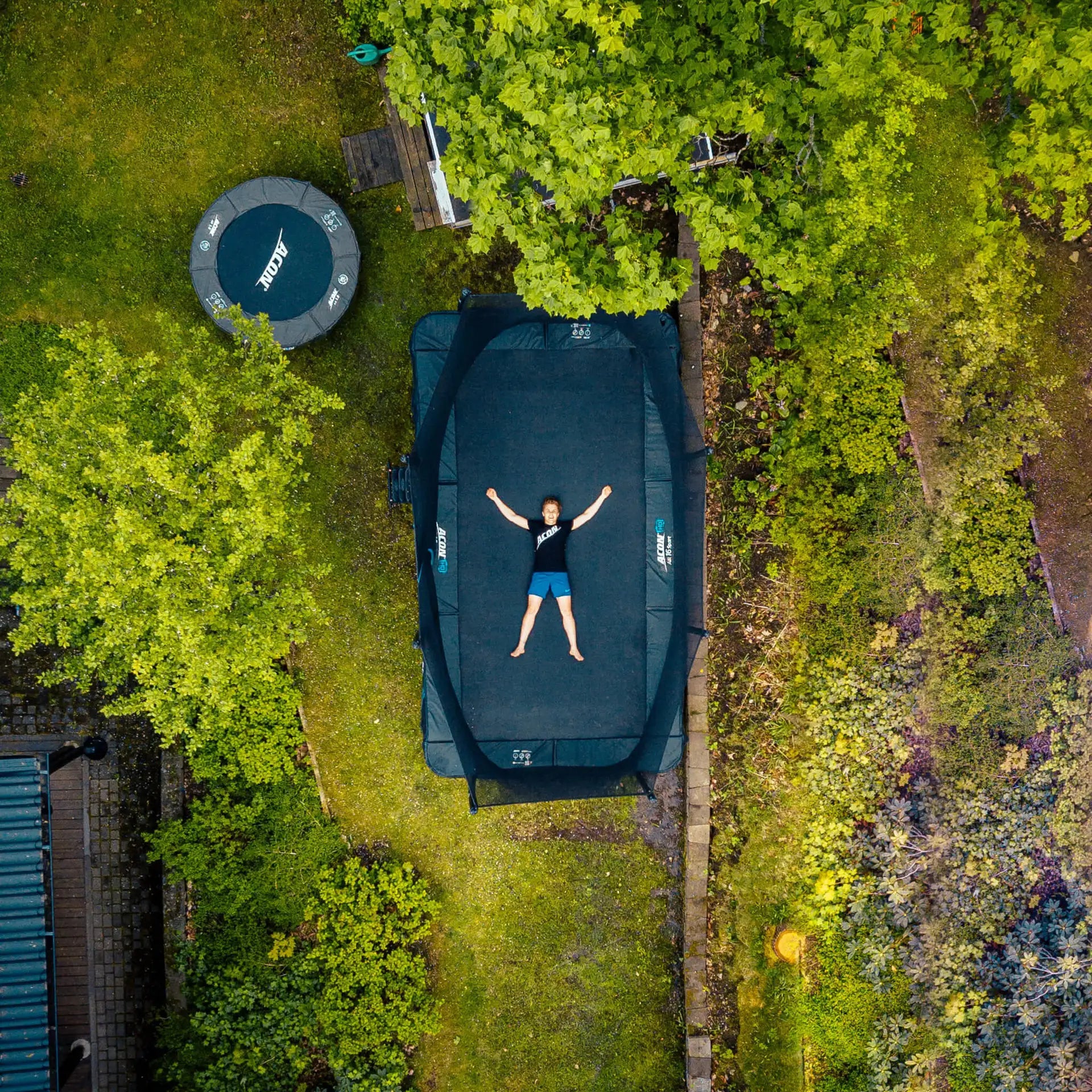 A boy laying on an Acon trampoline. Picture taken from bird's eye view.