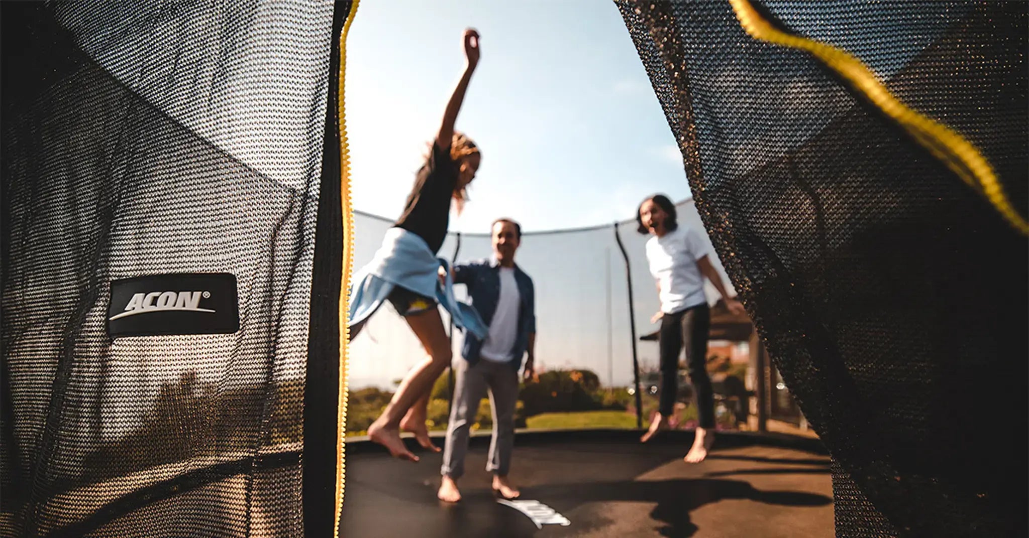 Happy family jumping on a Acon trampoline with safety net. 