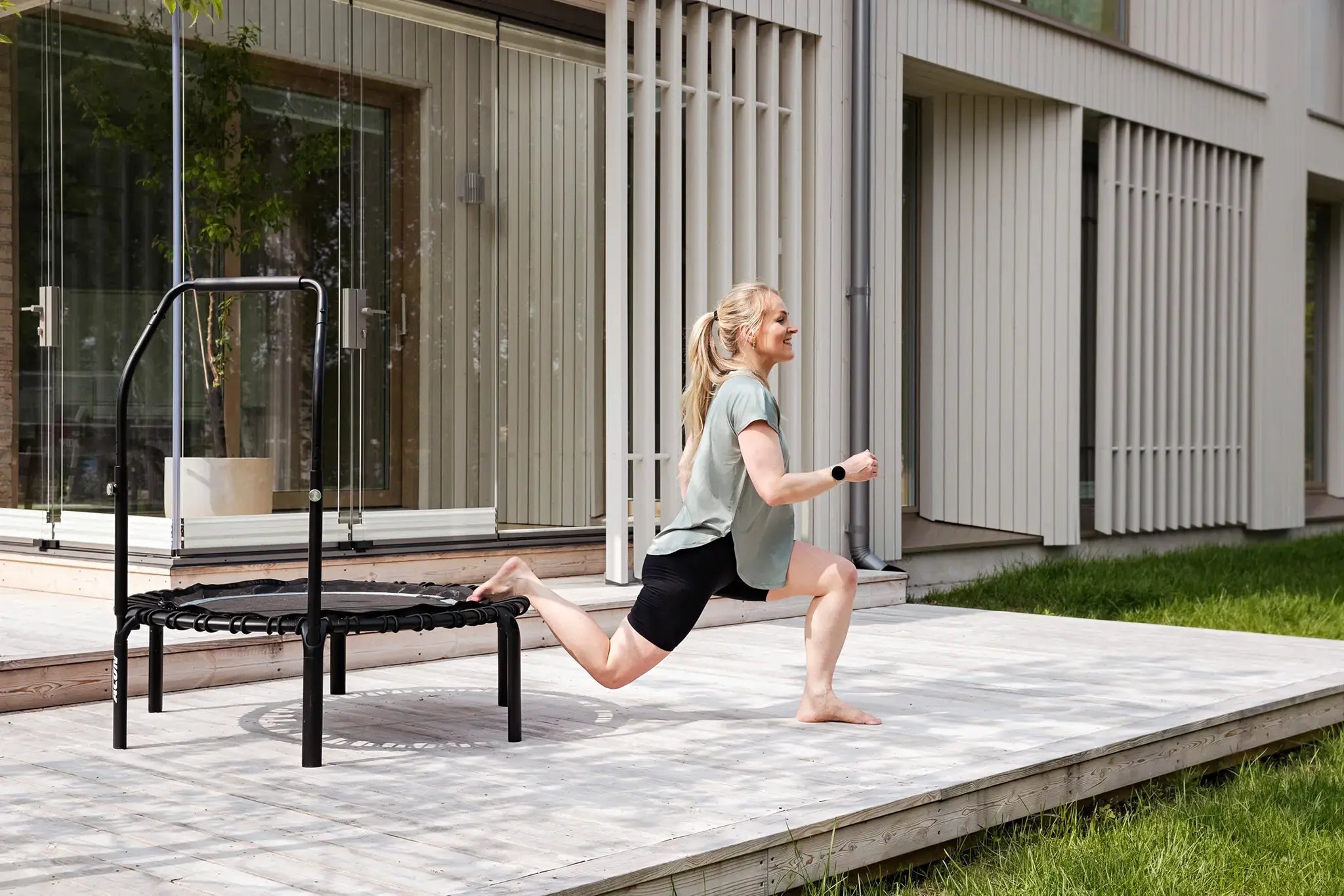 Woman does a split squat on a Acon rebounder trampoline. 