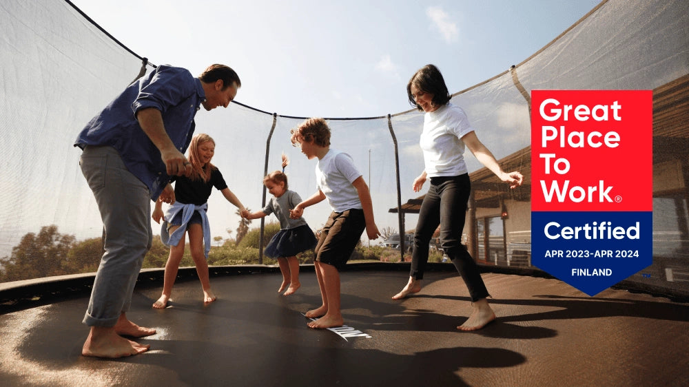 Family enjoying an Acon trampoline with the Great Place to Work certification badge displayed.