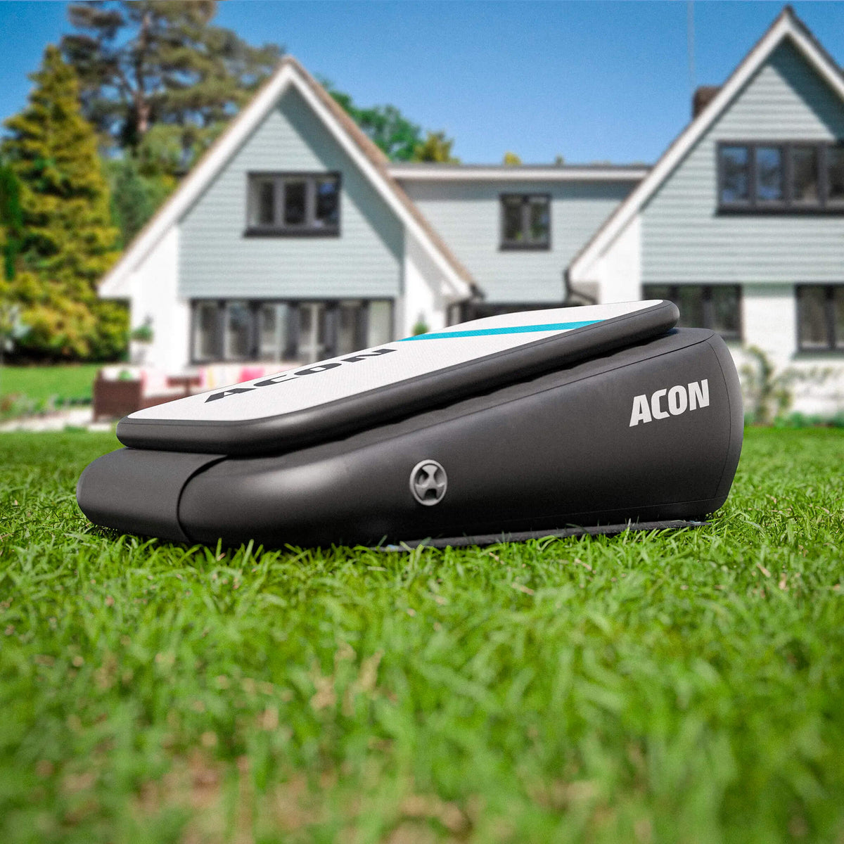 ACON Airboard on grass in a sunny backyard, with a large house in the background.