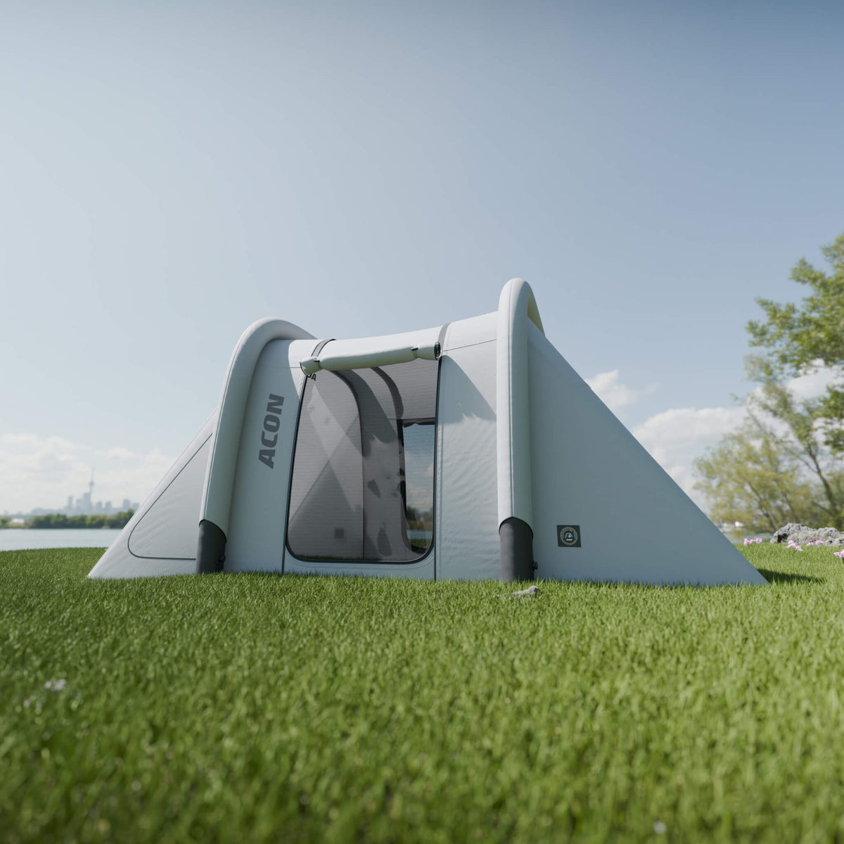 Acon rectangular trampoline tent set up on a lush green lawn, featuring gray and white colors with transparent mesh windows. The tent's design is sleek and modern, positioned under a clear blue sky, highlighting its outdoor suitability and spacious interior.