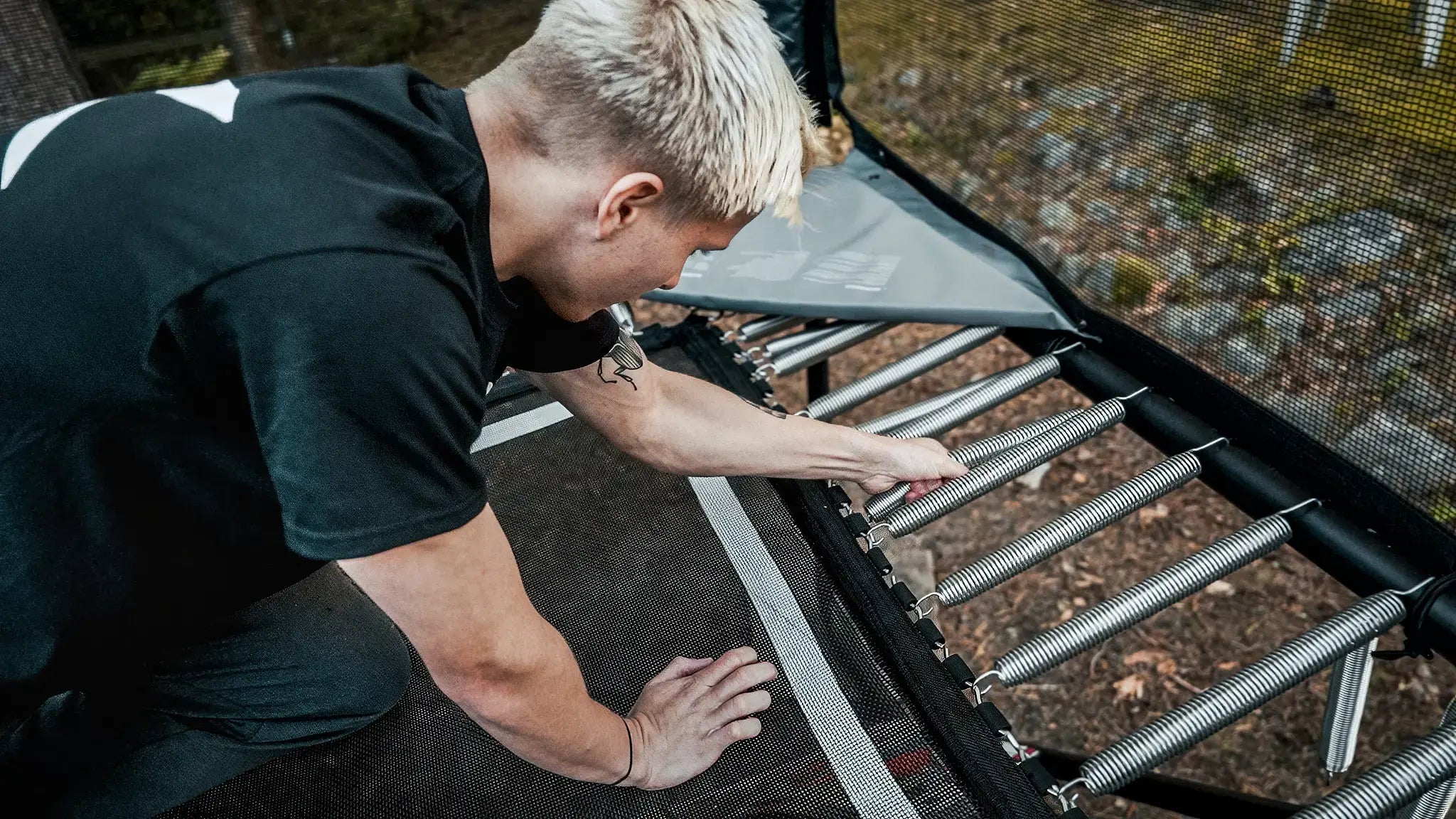Boy is adjusting Acon X trampoline springs. 