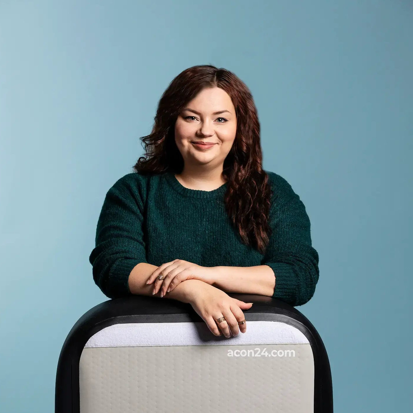 Acon's Communication Manager Janita Tuohino leaning her arms on an ACON airtrack against a light blue background.