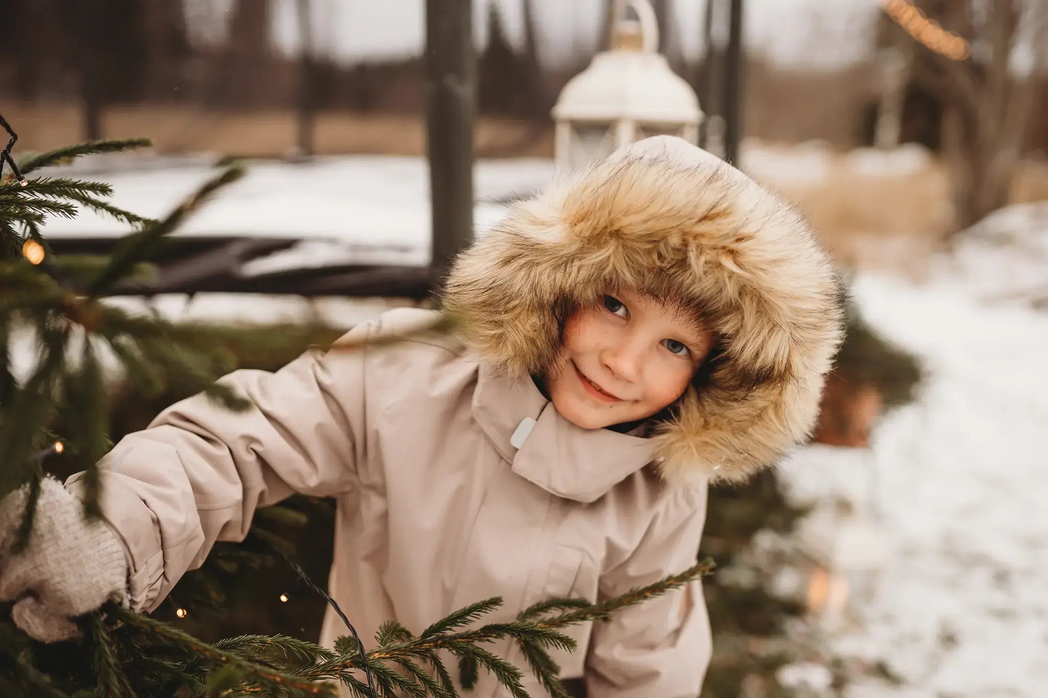 Happy child wearing a thick winter coat looking at the camera , with Acon trampoline in the background. 