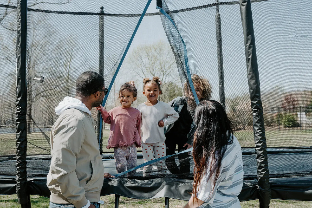 Family spending time together around an ACON backyard trampoline.