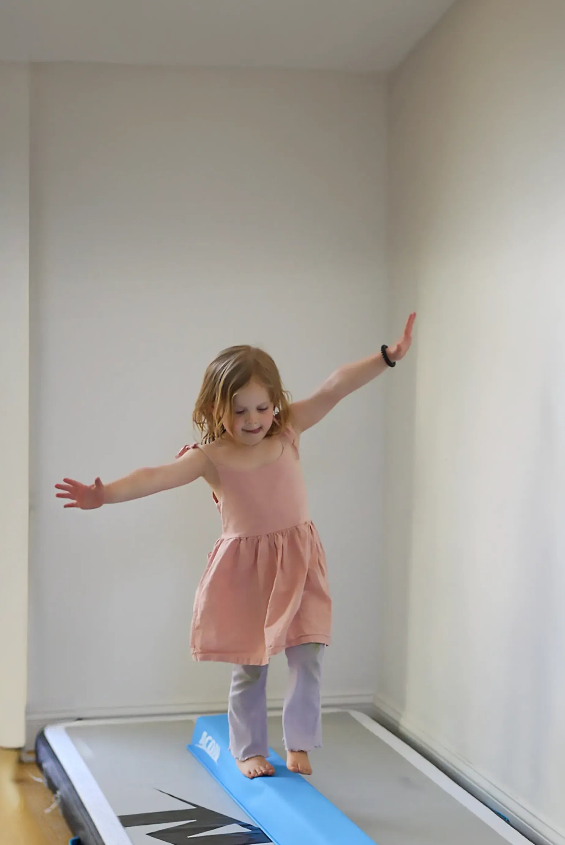 A little girl balances on an Acon Balance Beam and a 10-foot airtrack.
