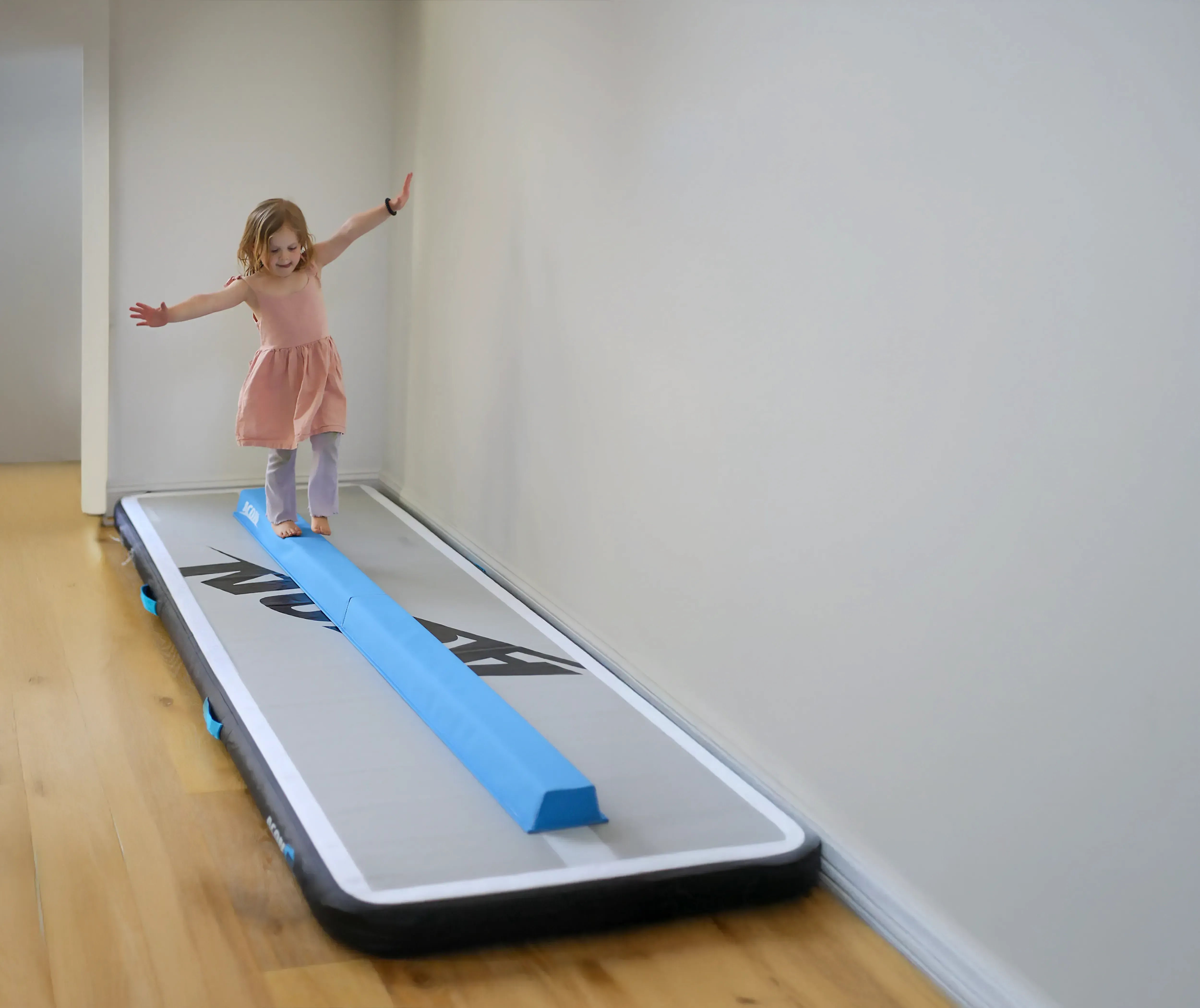 A little girl balances on an Acon Balance Beam and a 10-foot airtrack.