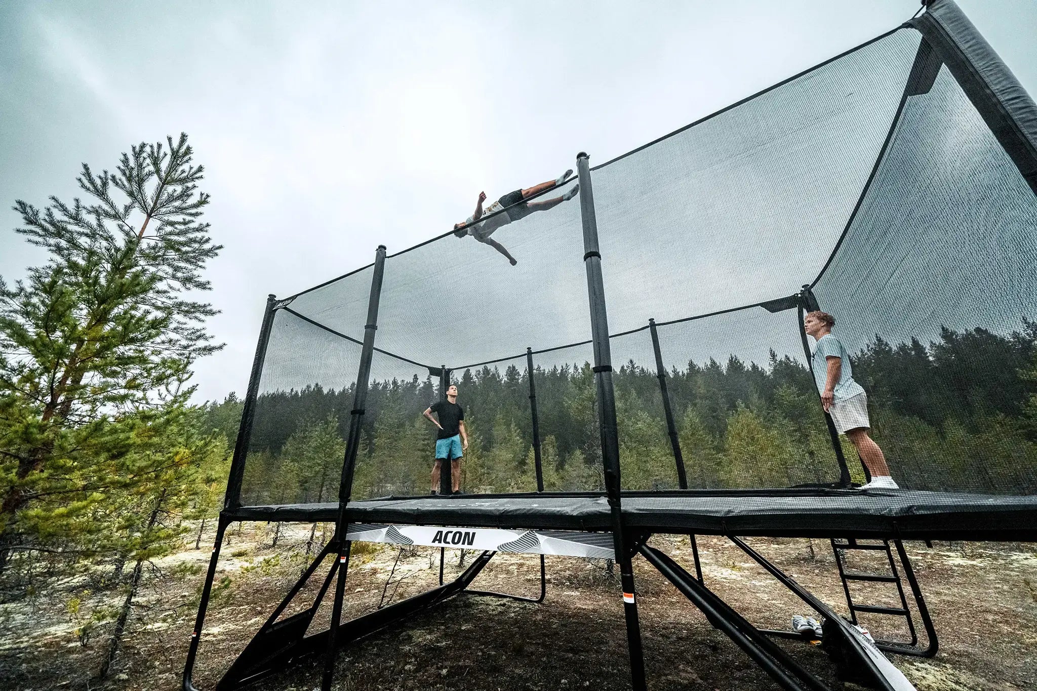Three gymnasts jumping on a Acon X trampoline in a forest. 
