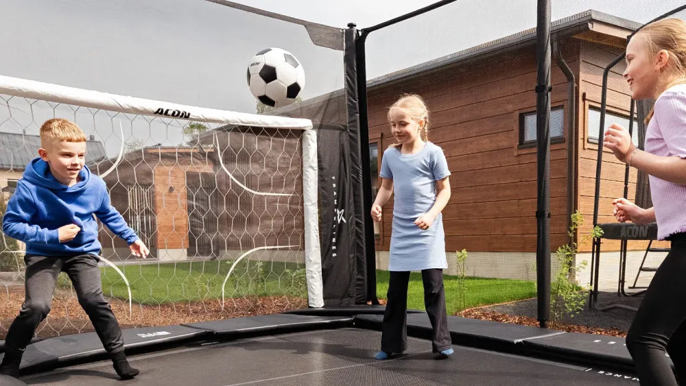 Children playing soccer on an Acon X trampoline with an ACON Soccer Goal.