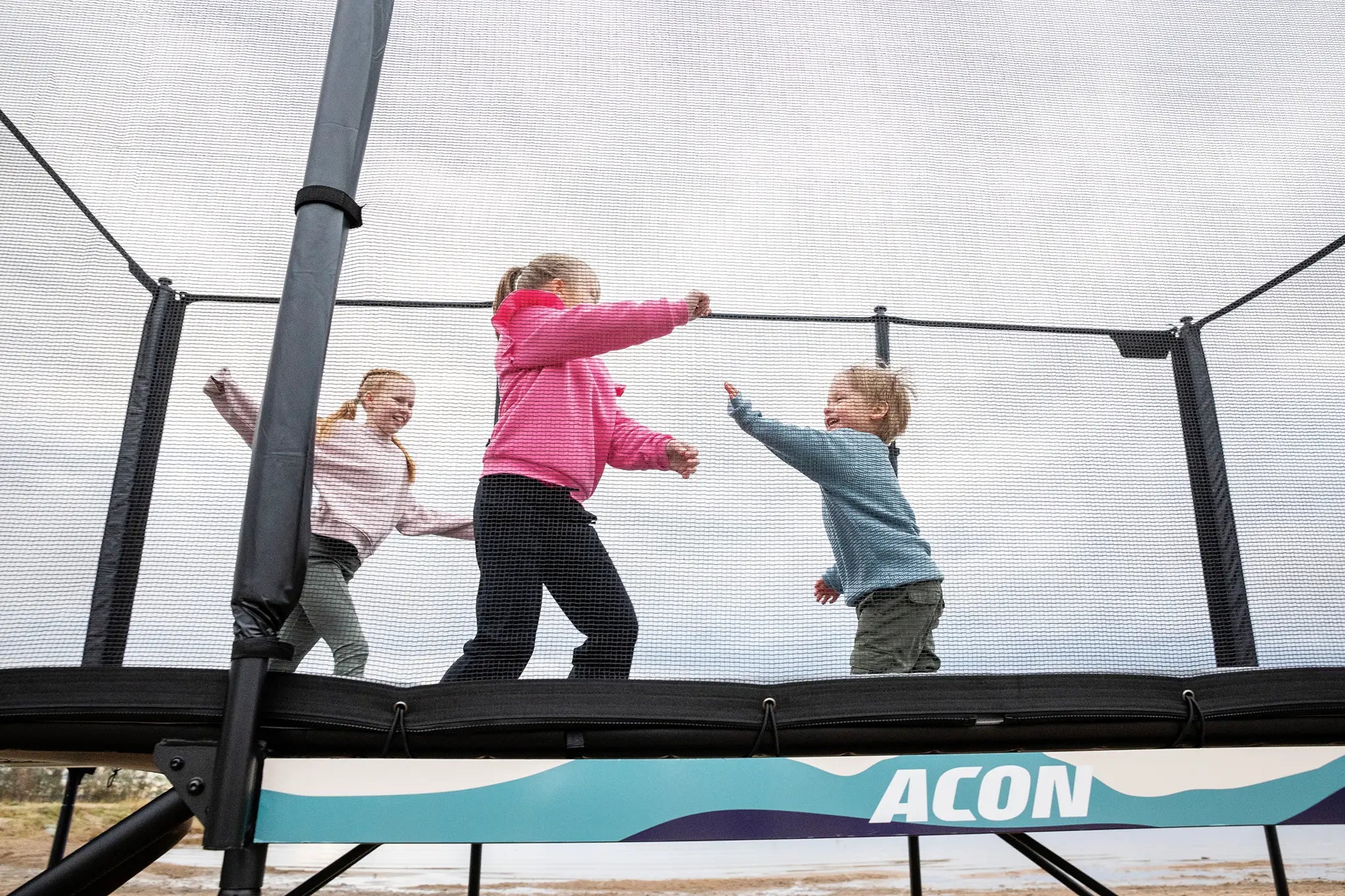 Three young kids playing on Acon X trampoline. 