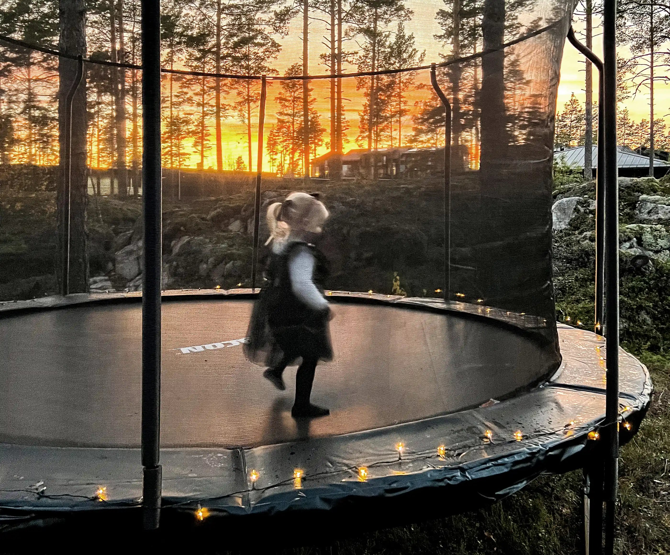 A little girl in Christmas clothing on an ACON round trampoline with enclosure.