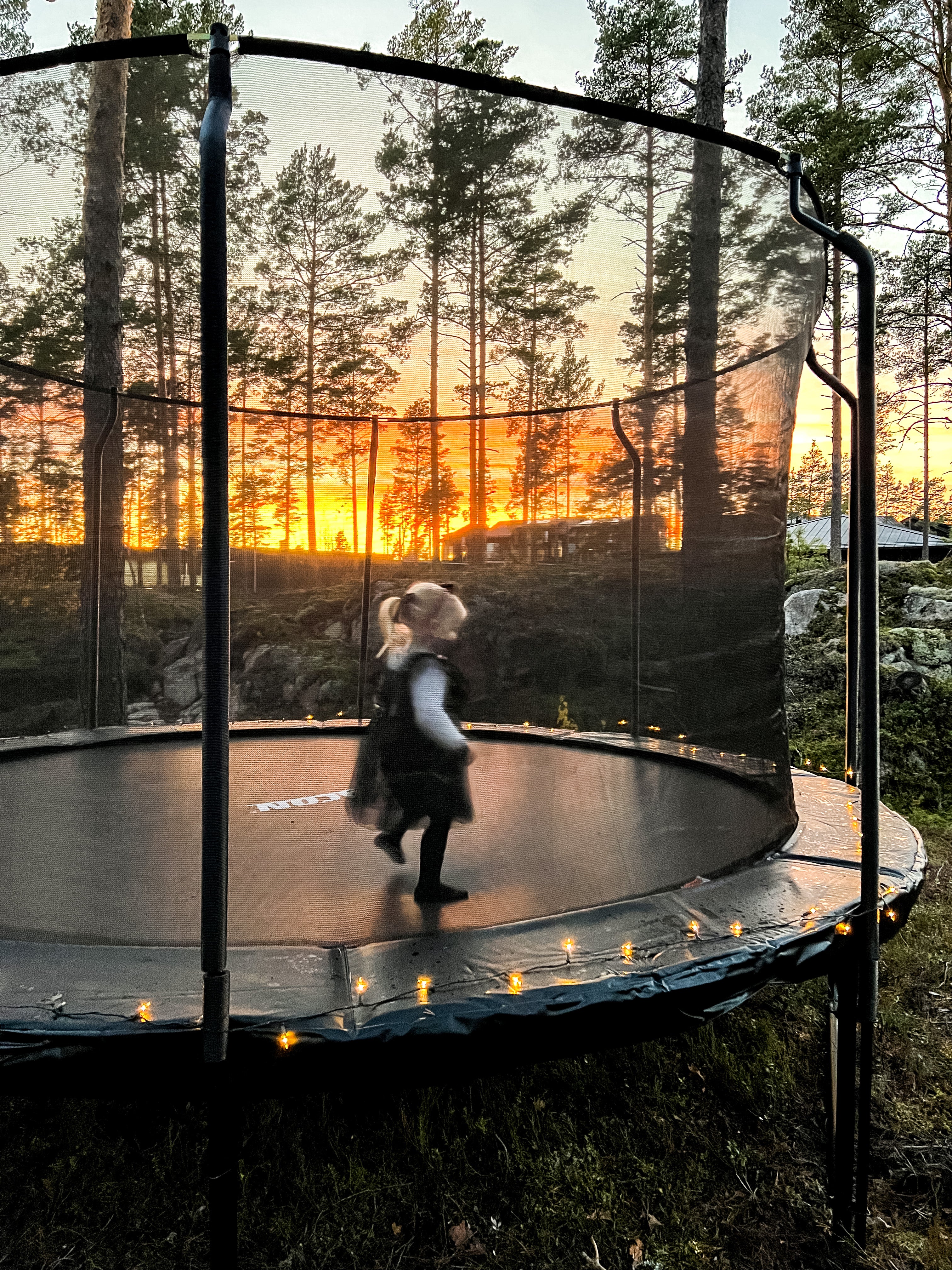 A little girl in Christmas clothing on an ACON round trampoline with enclosure