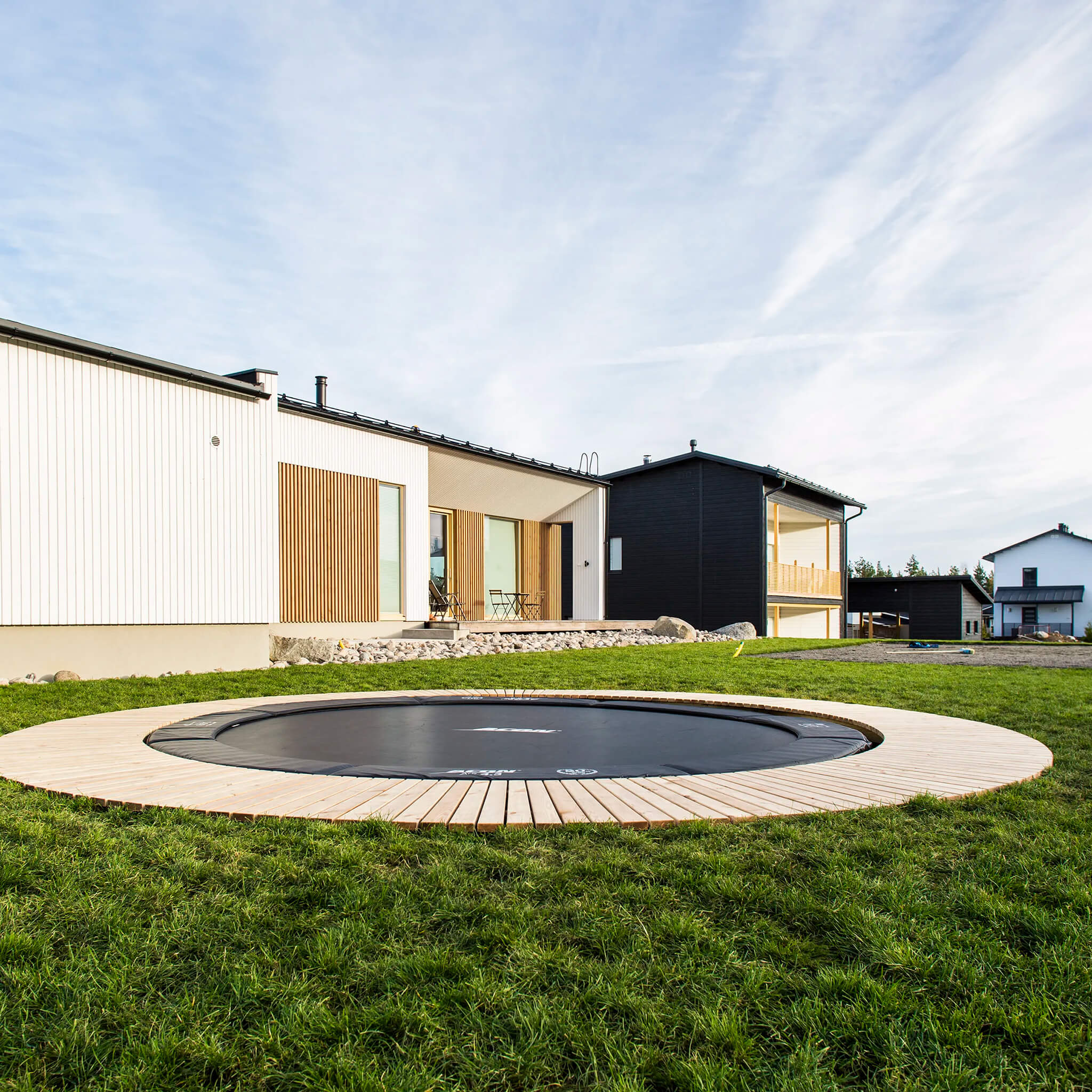 Ingrounded Acon Trampoline, surrounded with wooden panels.