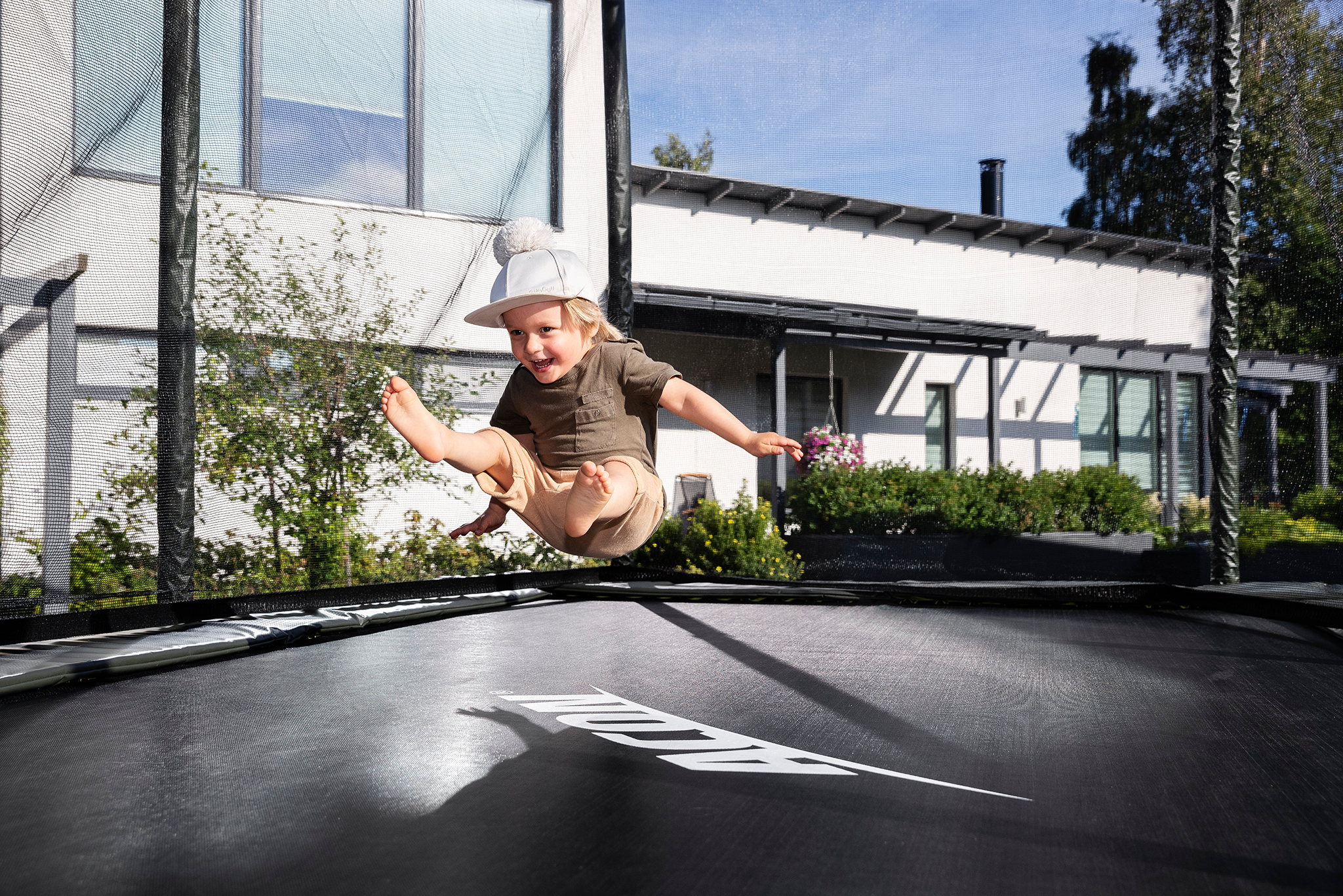Young boy jumping on a rectangular Acon trampoline with safety net. 