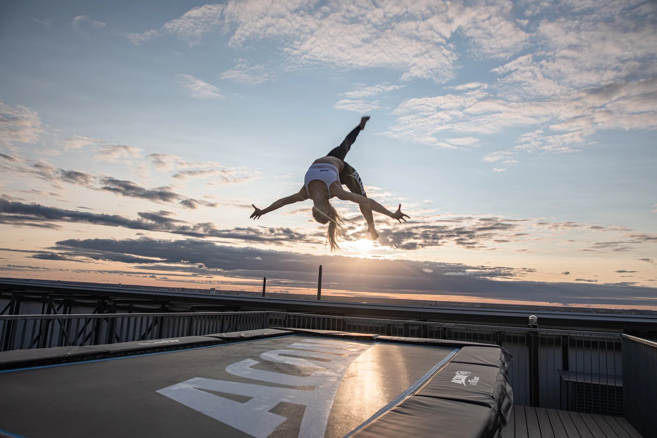 A woman jumping on an Acon HD trampoline in a sunrise.