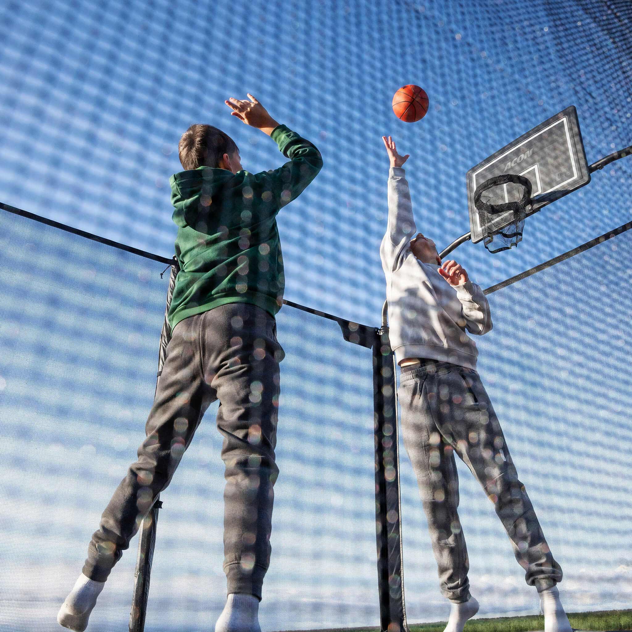 Two boys play basketball on the Acon X Trampoline.